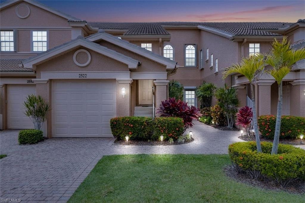 Townhome featuring an attached garage, paver driveway, and tiled roof