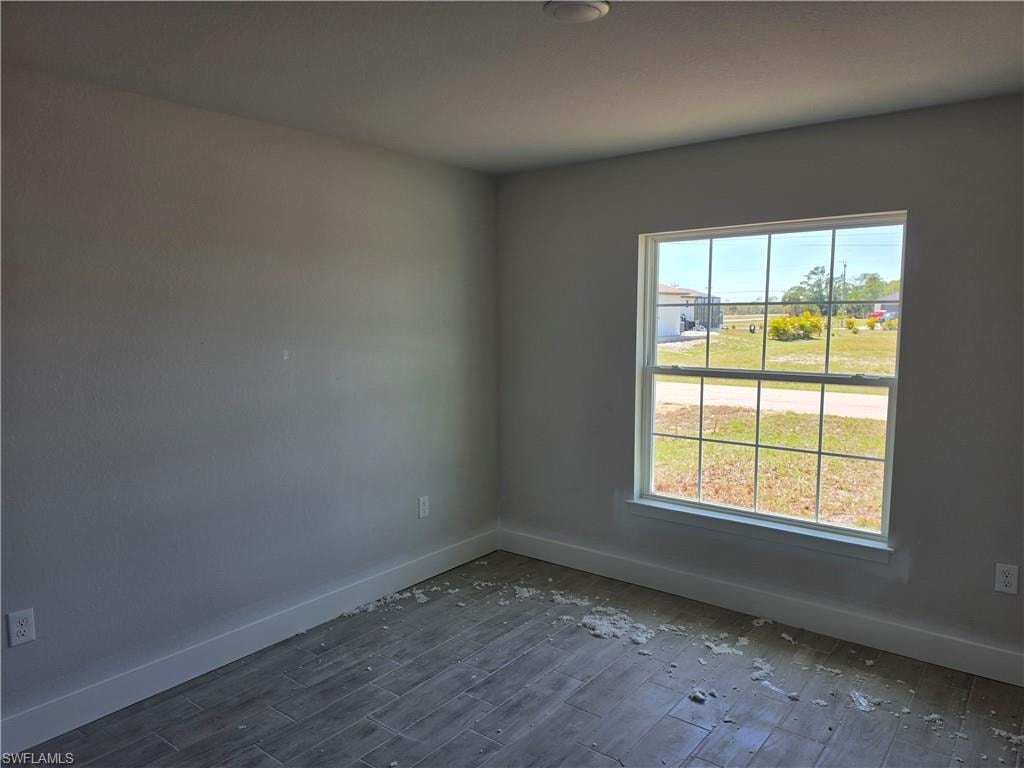 Room featuring a large grid-pattern window, light gray walls, white baseboards, and wood-finish tile flooring
