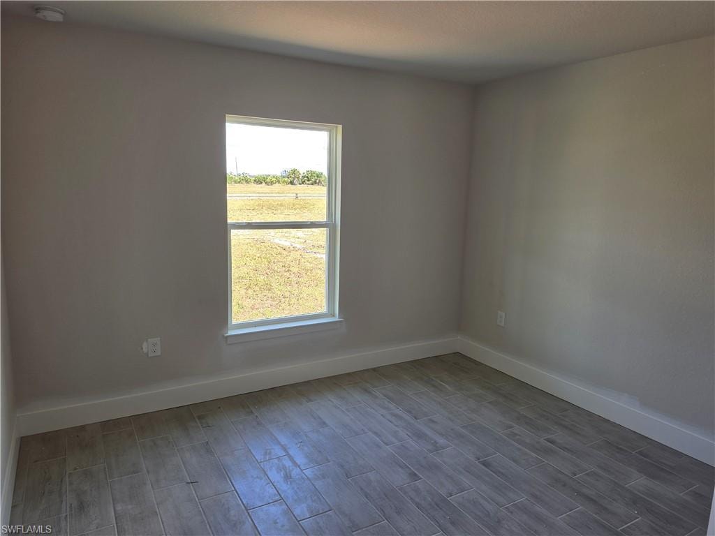 Room featuring wood-look tile flooring, neutral wall tones, white trim, and a double-hung window
