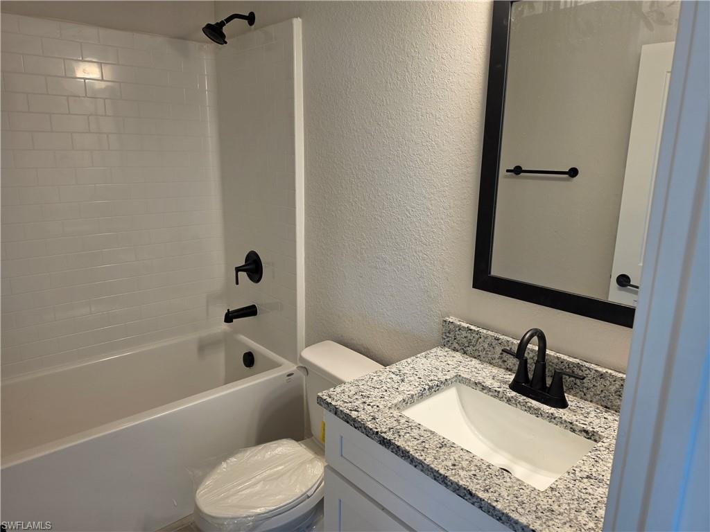 Bathroom featuring a white subway tile tub surround, dark bronze fixtures, a granite countertop vanity, and a framed mirror