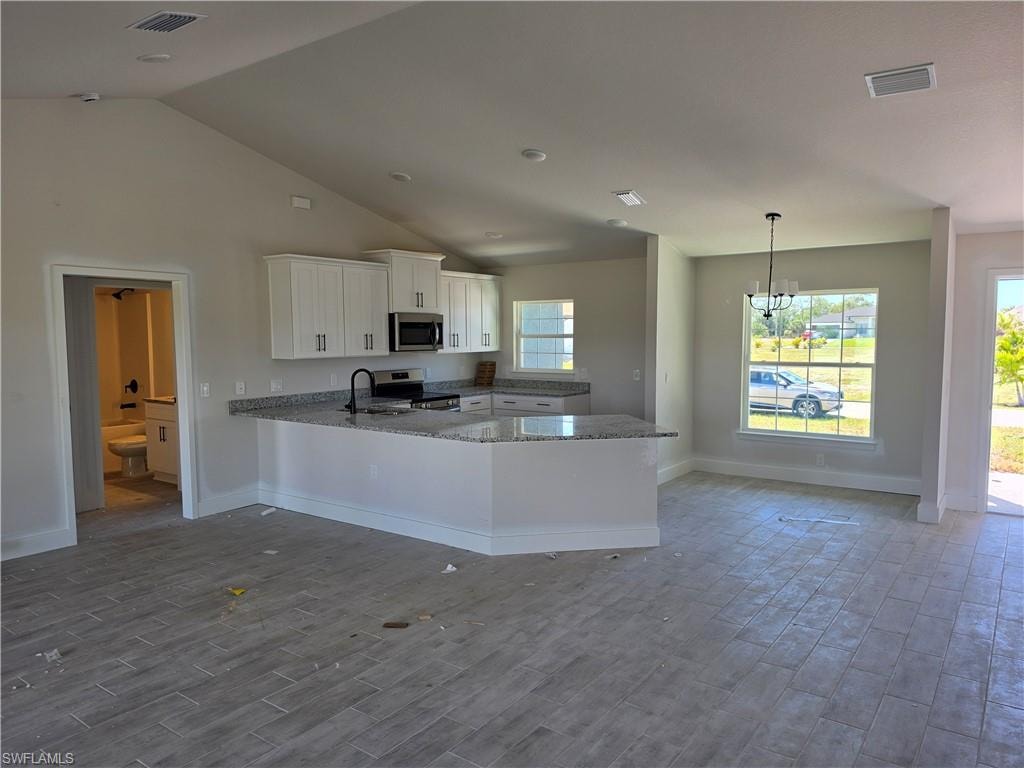 Open-concept living space featuring vaulted ceilings and wood-finish flooring