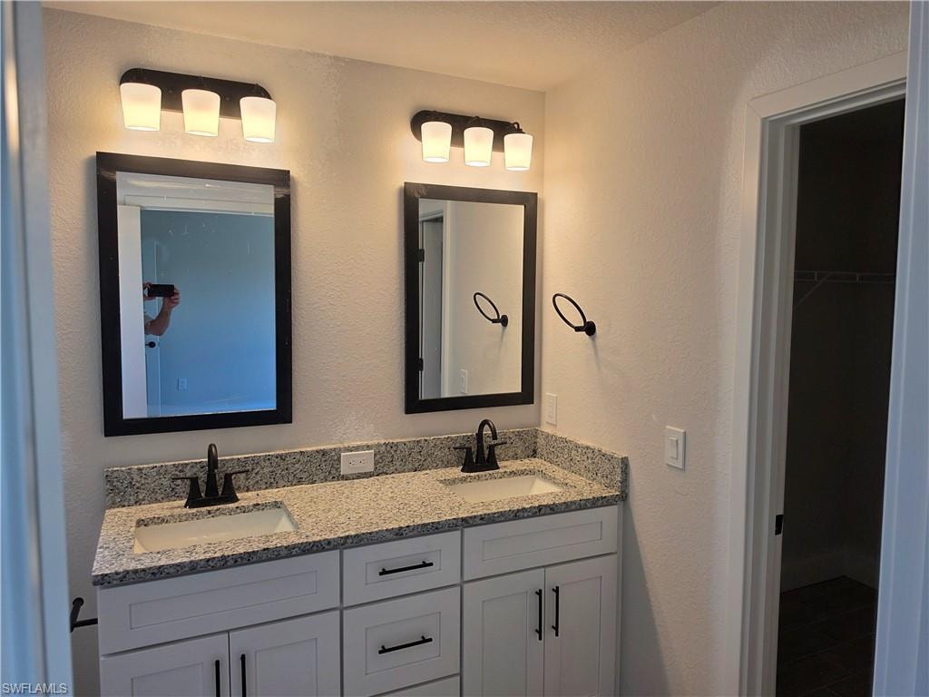 Dual white shaker vanity with granite countertops, integrated sinks, and matte black fixtures