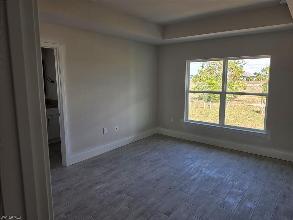 Room featuring a tray ceiling, tile flooring, and a large window with white trim