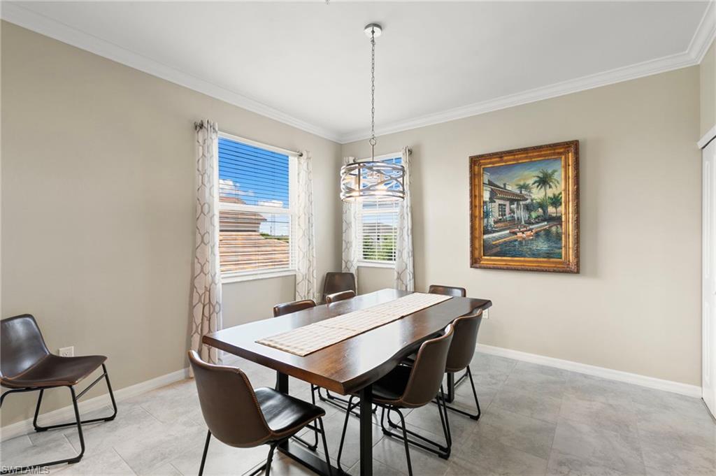 Dining area featuring wood-finish table with metal base, contemporary chandelier, and light gray tile flooring