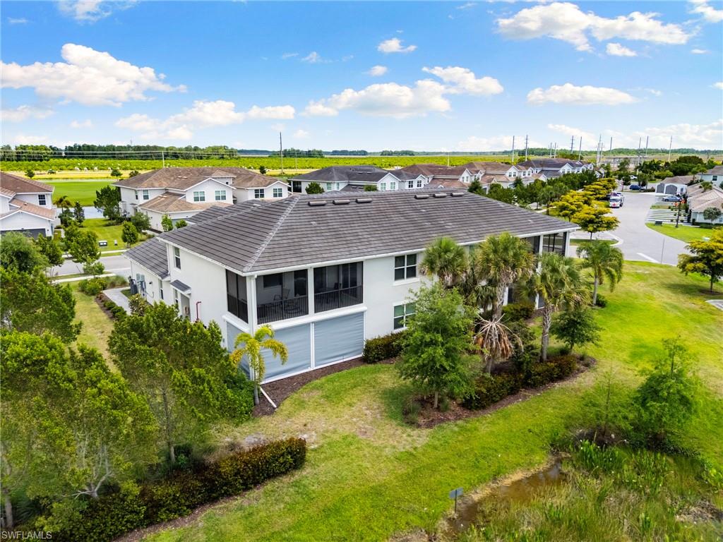 Two-story residence featuring a screened-in upper-level balcony, a lower-level screened patio with roll-down hurricane shutters, and a tile roof