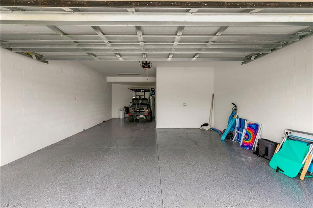 Spacious garage featuring a durable epoxy floor coating, painted block walls, and a visible garage door opener mechanism