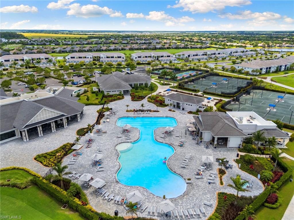 Expansive amenity center featuring a resort-style pool with integrated spa, multiple tennis courts, and several low-rise recreational buildings