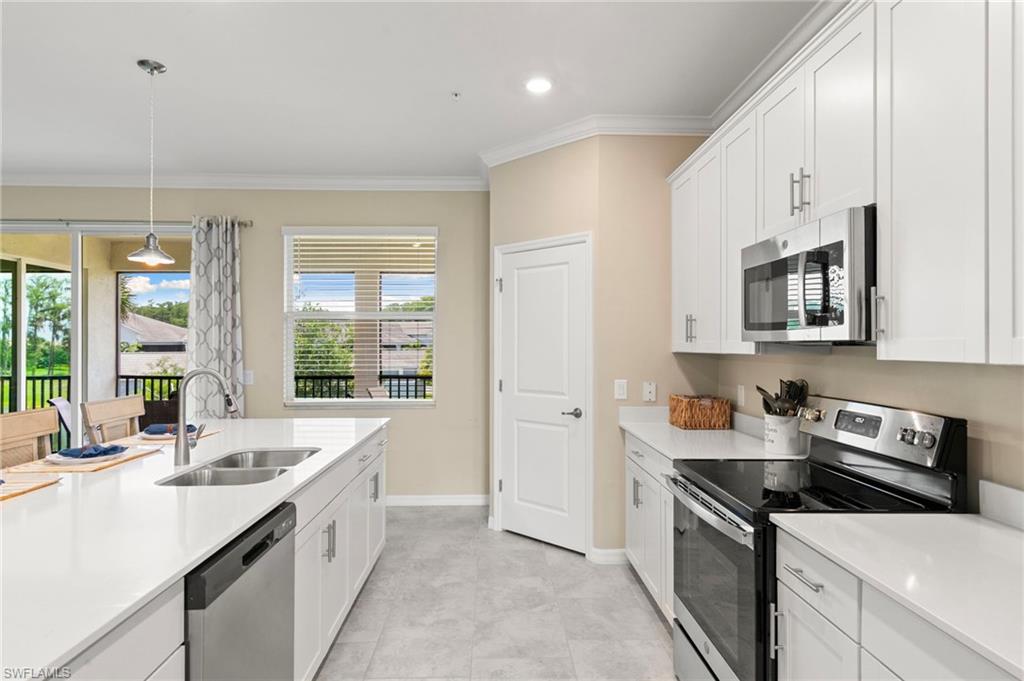 Modern kitchen featuring white cabinetry, light-colored countertops, stainless steel appliances, and a central island with an undermount sink