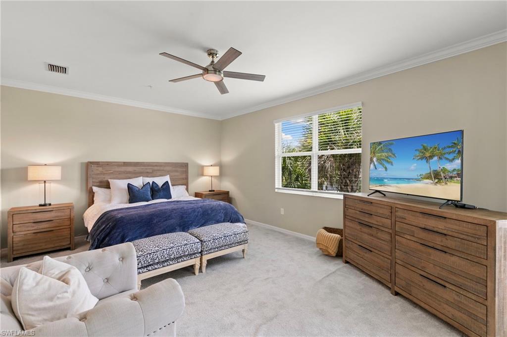 Spacious bedroom featuring light-colored walls, crown molding, a window with horizontal blinds, and carpeted flooring