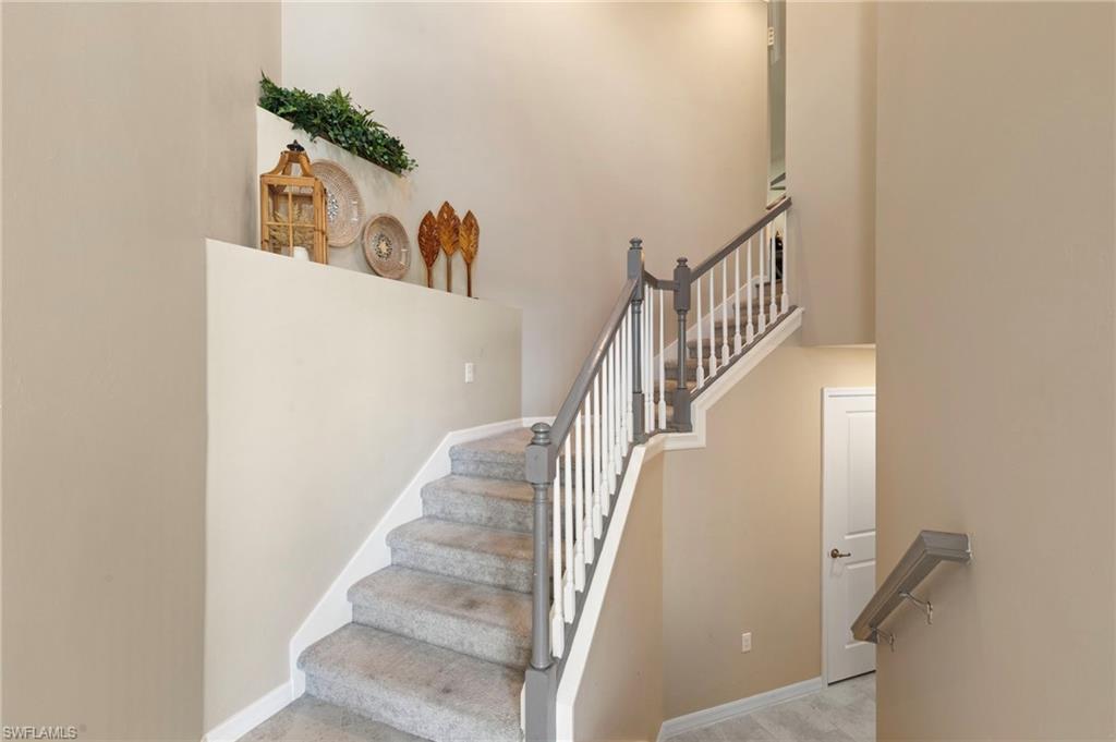Carpeted staircase featuring painted balusters and dark-toned handrails