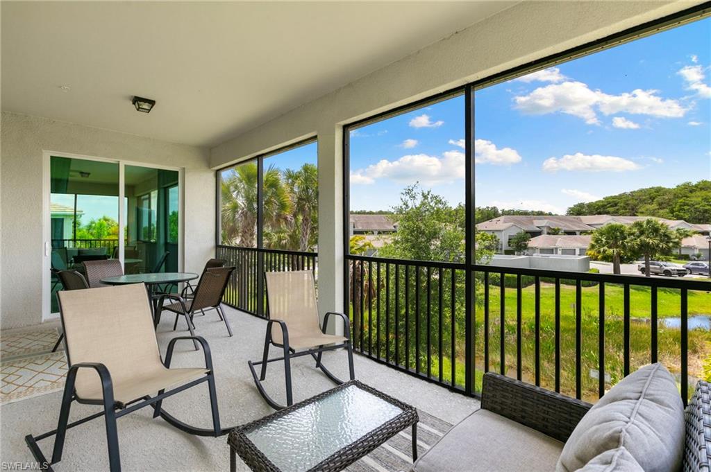 Expansive screened lanai featuring a textured concrete floor, black metal railing, and a sliding glass door entry