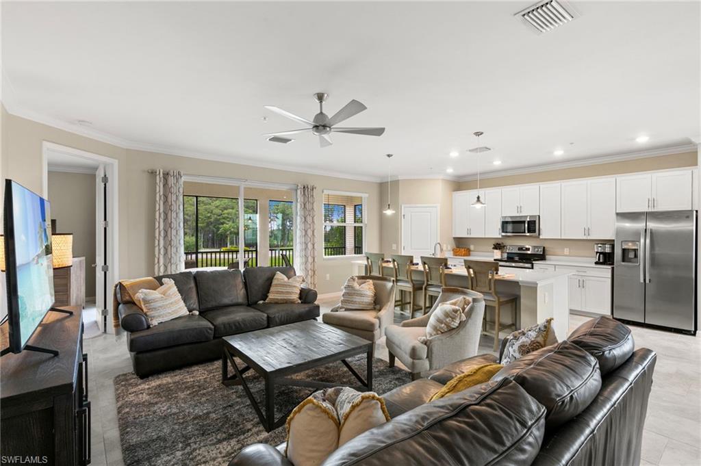 Open-concept living space featuring light tile flooring, a ceiling fan, and sliding glass doors leading to an exterior balcony
