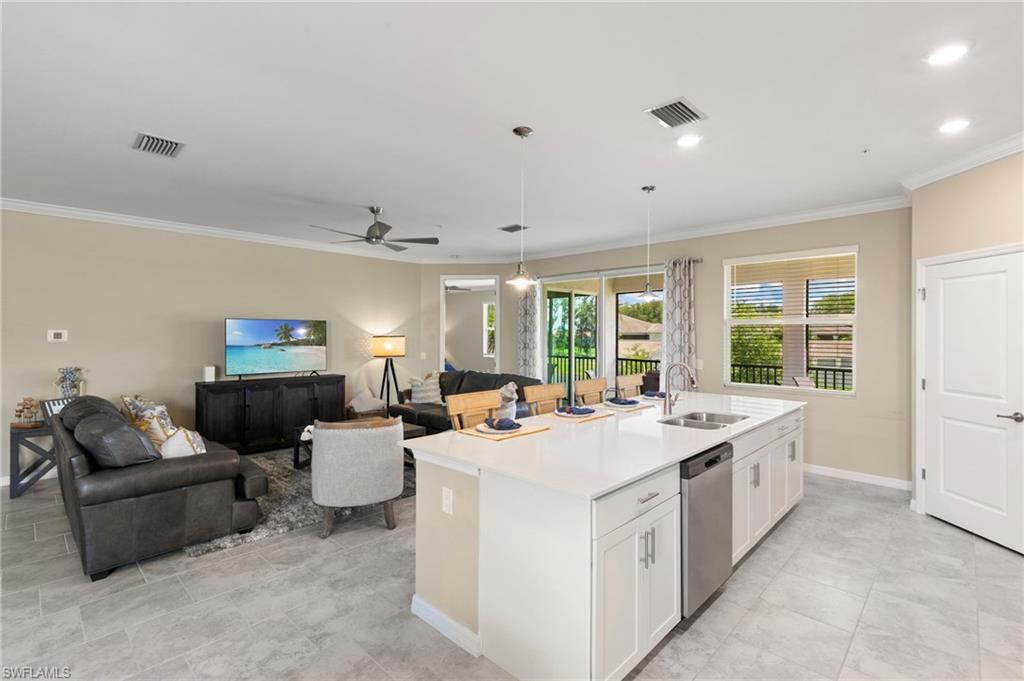 Spacious open-concept living area featuring a kitchen island with seating, stainless steel appliances, recessed lighting, and tile flooring
