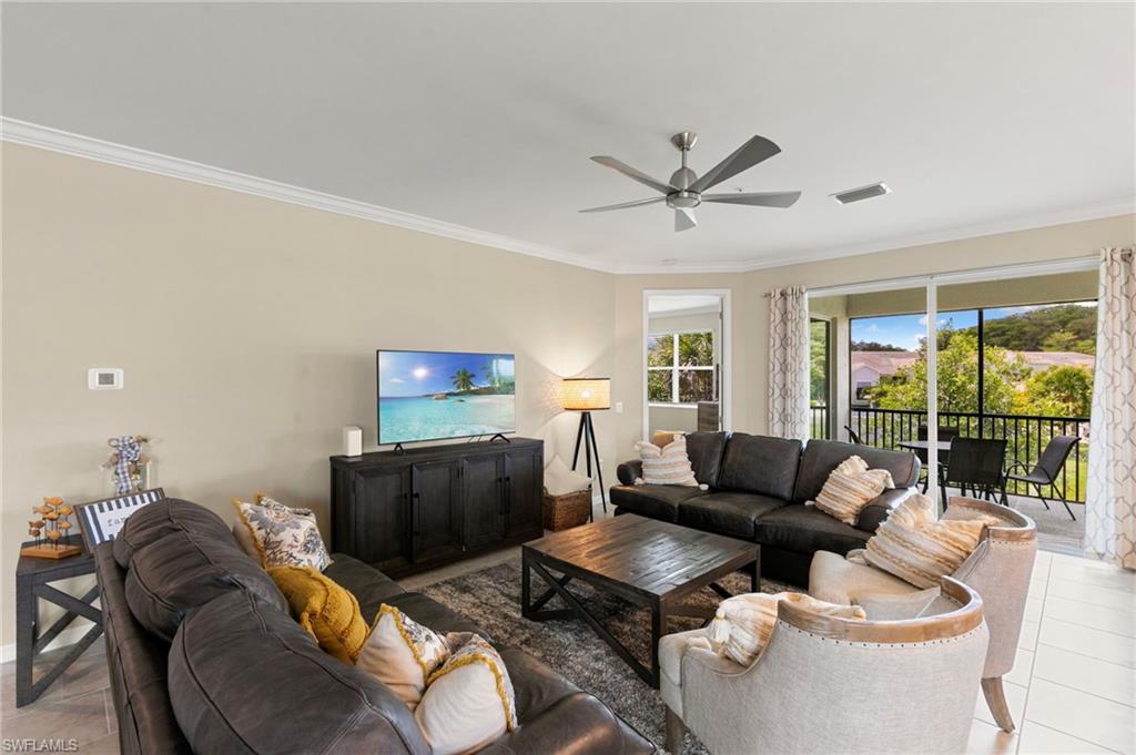 Spacious living area featuring neutral wall tones, crown molding, and a ceiling fan