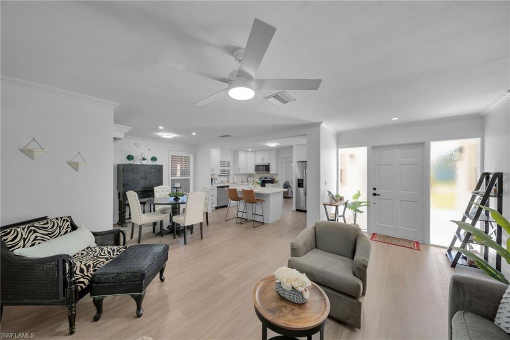 Open-concept living area featuring wood-finish flooring, white walls, and a ceiling fan
