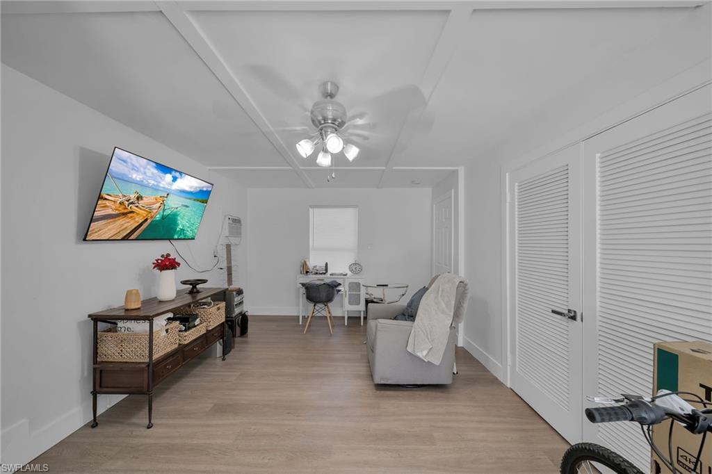 Spacious room featuring light wood-finish flooring, white walls, and a ceiling fan with integrated lighting