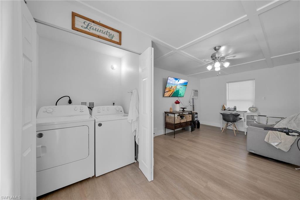 Dedicated laundry closet with white appliances, complemented by wood-finish flooring extending into the adjacent living space