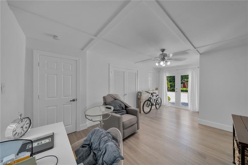 Spacious room featuring light wood-finish flooring, white walls, and a coffered ceiling
