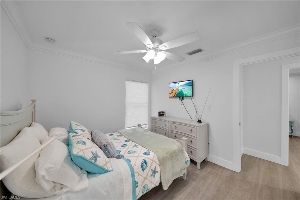 Room featuring wood-finish flooring, white walls, and crown molding