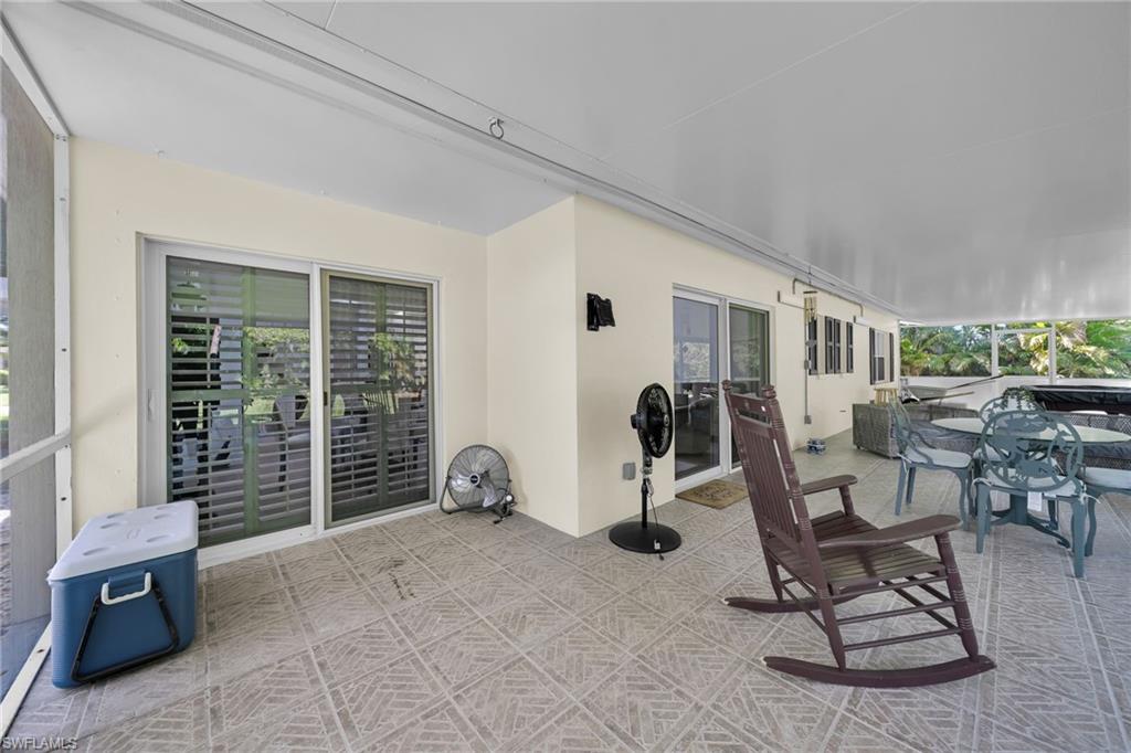 Expansive screened patio featuring patterned tile flooring, a solid white ceiling, and multiple white-framed sliding glass doors with louvered blinds