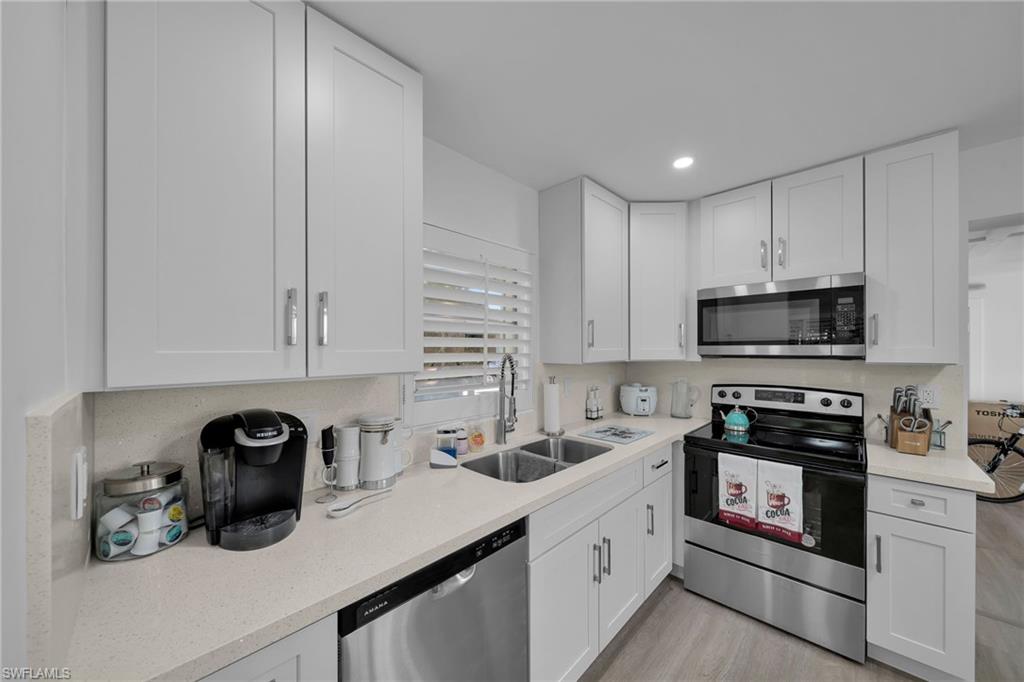 Modern kitchen featuring white shaker cabinetry, light-toned countertops, and stainless steel appliances