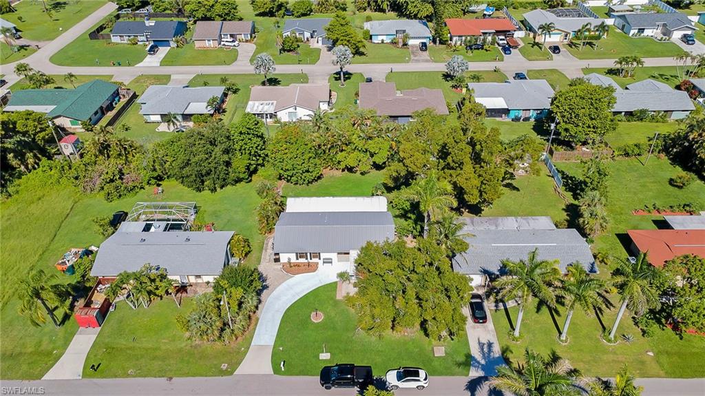 Aerial perspective highlighting a residential property with a light gray roof and an elongated concrete driveway