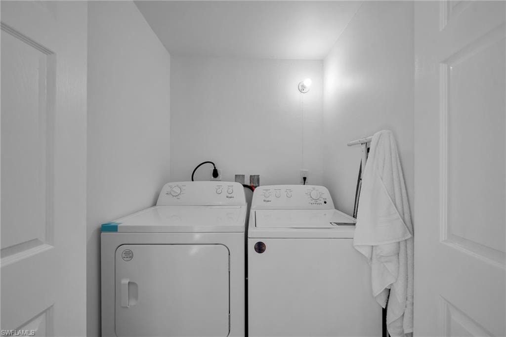 Dedicated laundry area featuring white appliances, a wall-mounted light fixture, and neutral painted walls