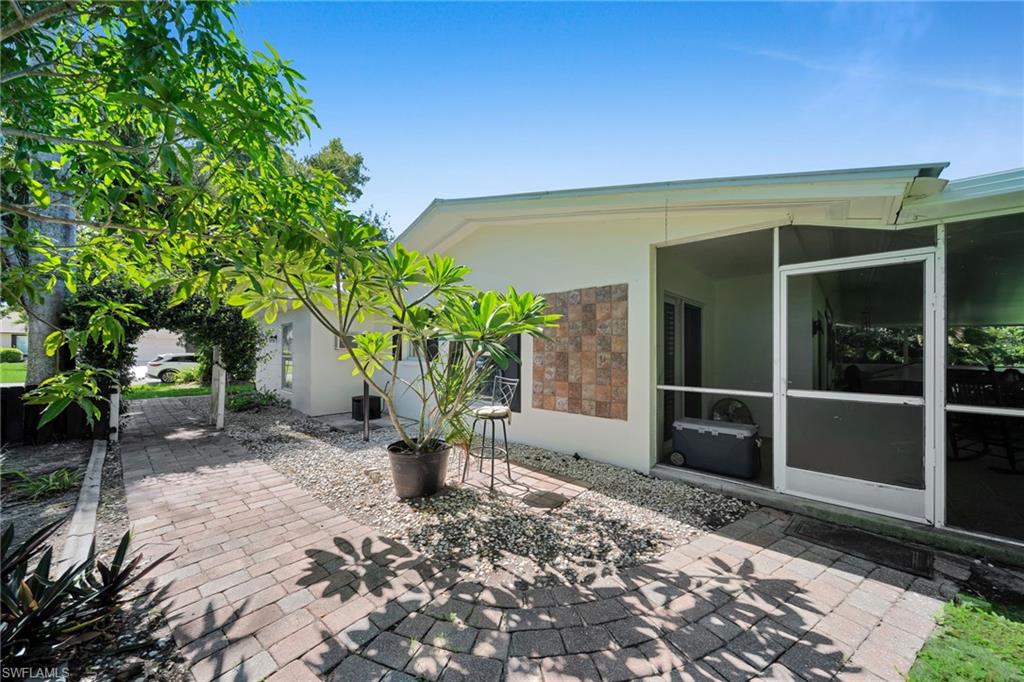 Expansive paver patio leading to a screened lanai with a textured accent wall