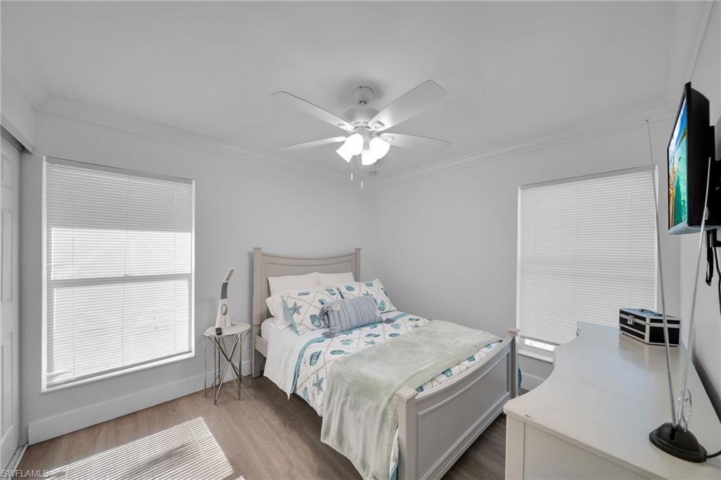 Bright room featuring a ceiling fan, crown molding, and two windows with blinds