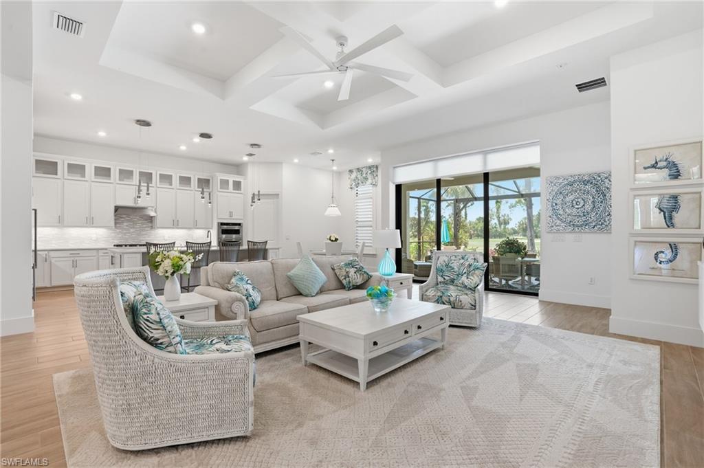 Open-concept living space featuring a tray ceiling with a ceiling fan, recessed lighting, and wood-finish flooring