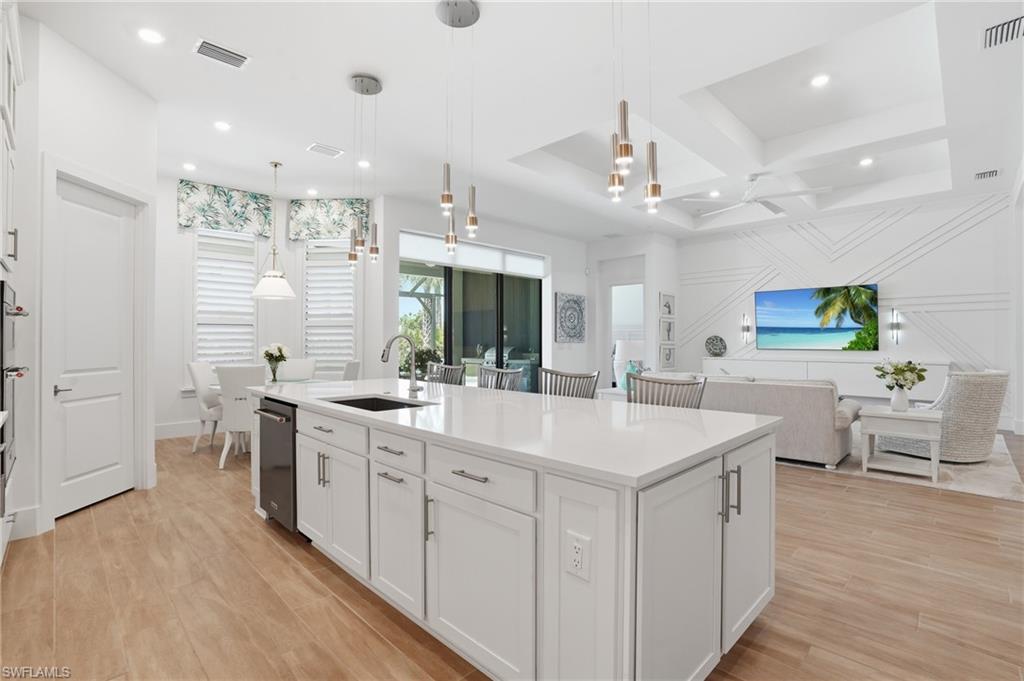 Open-concept living space featuring a substantial kitchen island with a white countertop, recessed lighting, and wood-finish flooring