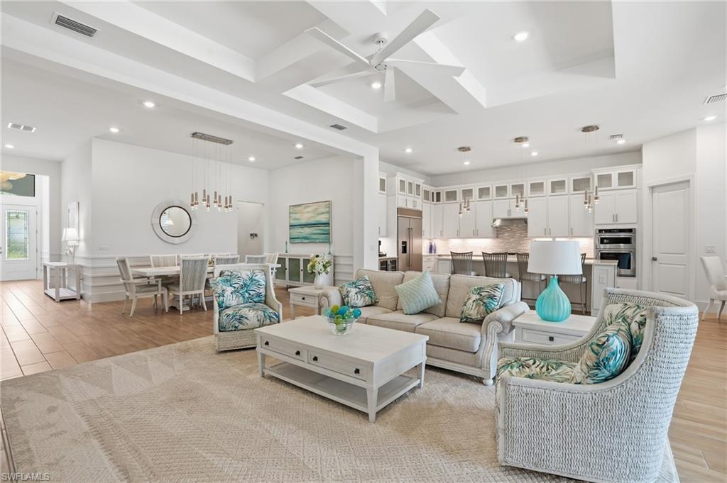 Spacious open-concept living area featuring a tray ceiling with a contemporary fan, recessed lighting, and wood-finish flooring