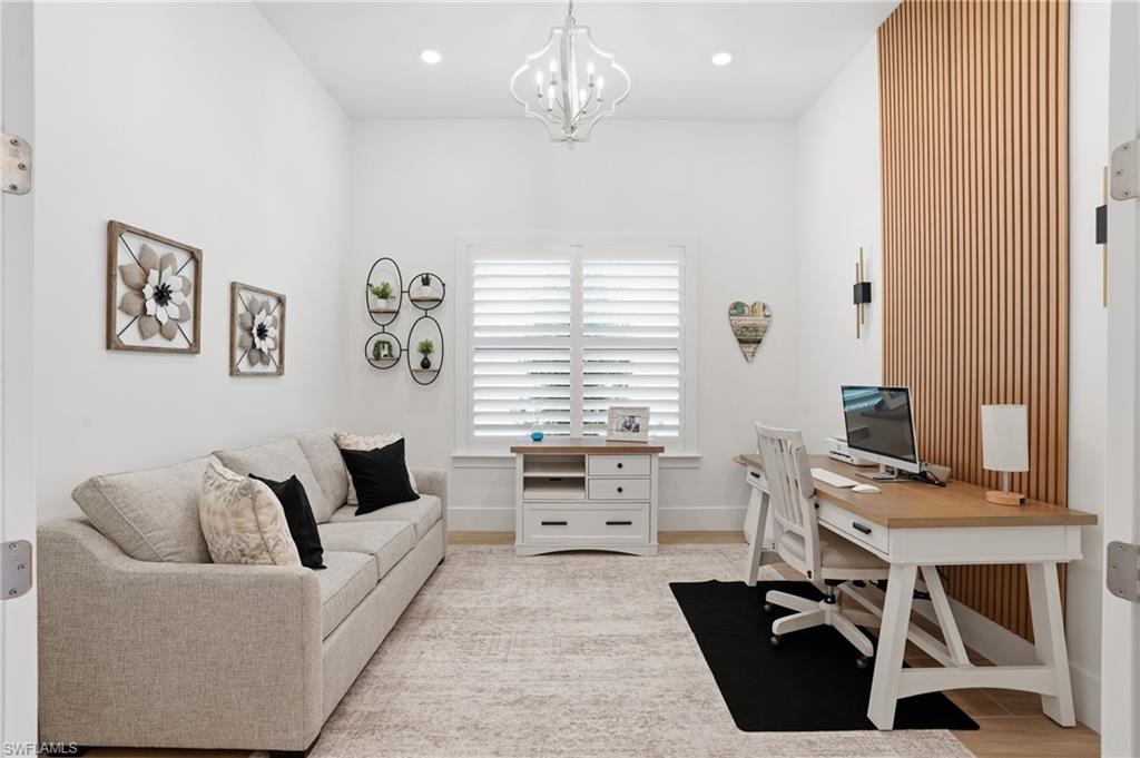 Spacious interior room featuring a decorative wood slat accent wall, recessed lighting, and a contemporary chandelier