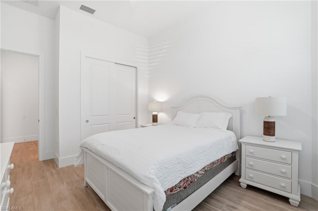 Bedroom featuring light wood-finish flooring, white walls, and a sliding bi-fold closet
