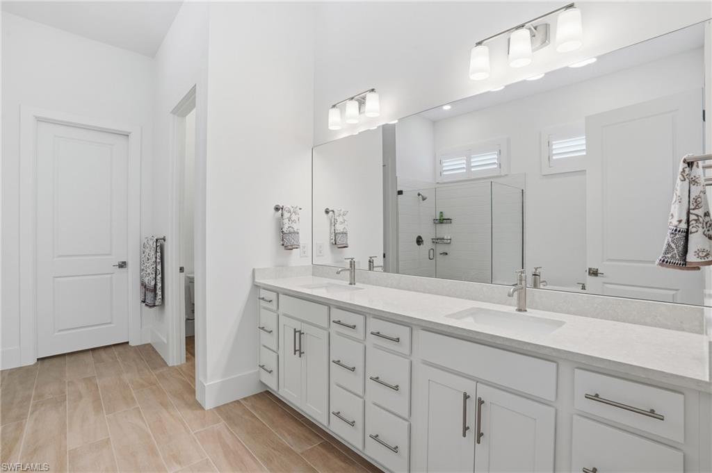 Spacious bathroom featuring a dual vanity with light-toned countertops, contemporary brushed nickel faucets, and extensive storage cabinetry
