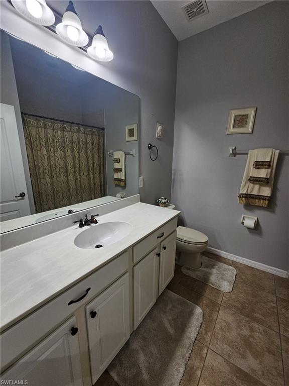 Bathroom featuring an extended vanity with a solid surface countertop, an integrated sink, and white cabinetry with dark hardware