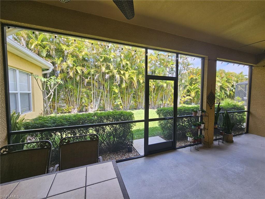 Screened lanai featuring a concrete floor, direct access to the yard, and surrounding lush tropical landscaping