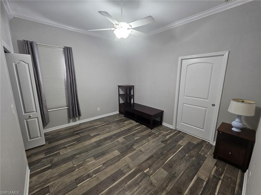 Room featuring wood-finish flooring, crown molding, and a ceiling fan