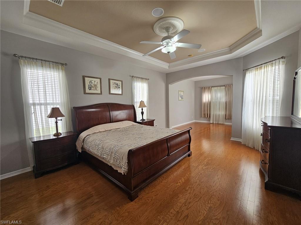 Spacious room featuring wood-finish flooring, a tray ceiling with crown molding, a ceiling fan, and recessed lighting