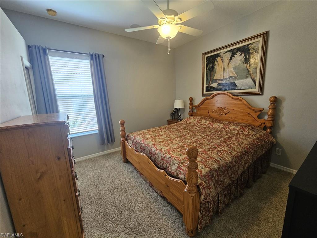 Recessed lighting and a ceiling fan fixture illuminate a room featuring neutral-toned walls and carpet flooring
