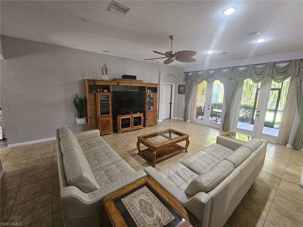 Spacious living area featuring large format tile flooring, recessed lighting, and a ceiling fan