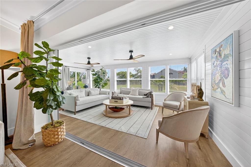 Sun-drenched living area featuring extensive window treatments, wood-finish flooring, and a white plank ceiling