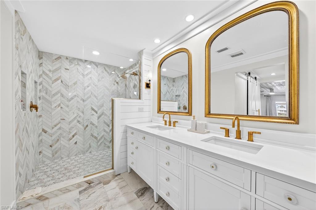 Dual vanity with white cabinetry, integrated sinks, and gold-finish fixtures