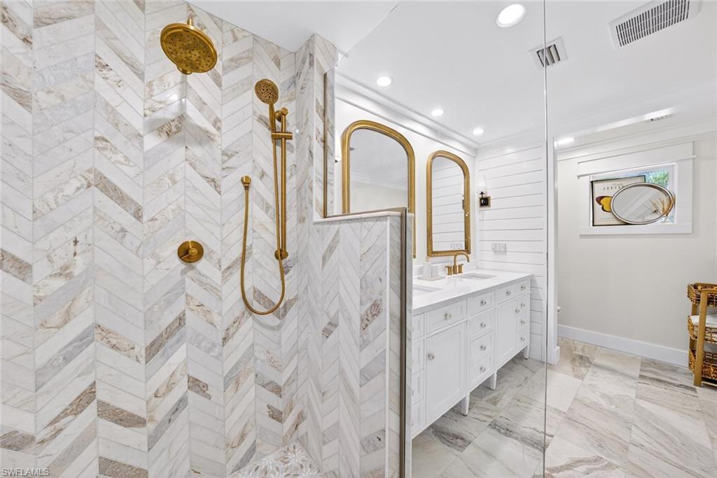 Shower with chevron-patterned tile work and brass fixtures
