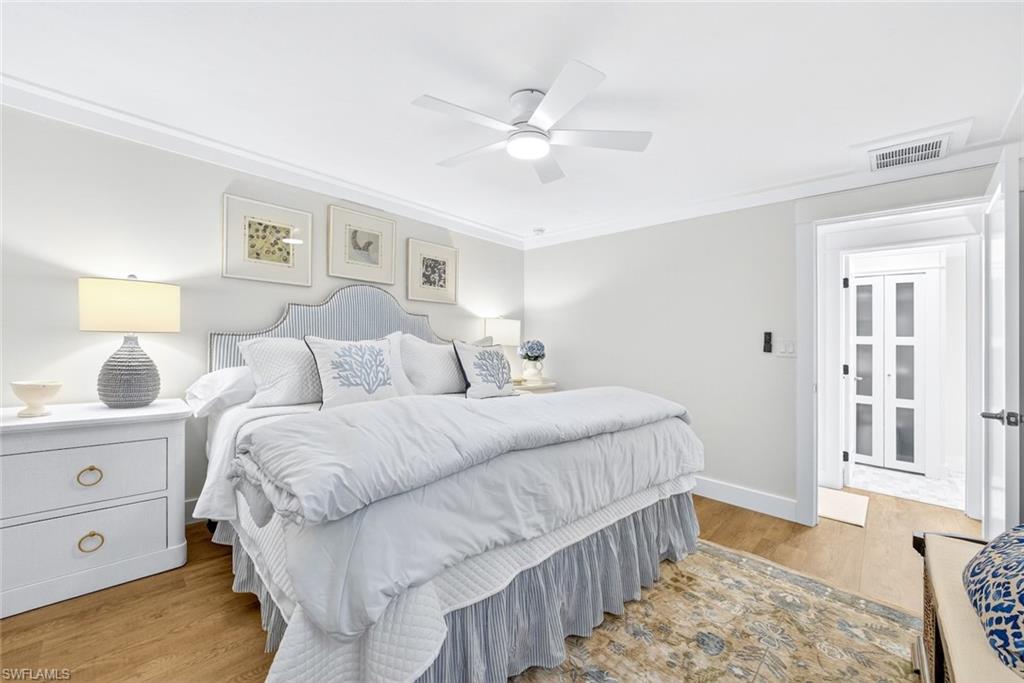 Spacious bedroom with wood-finish flooring and crown molding