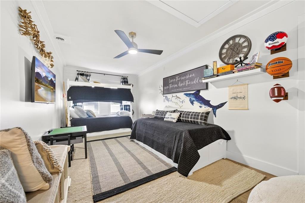 Spacious room featuring a bunk bed, a single bed frame, a ceiling fan, a wall-mounted television, and crown molding