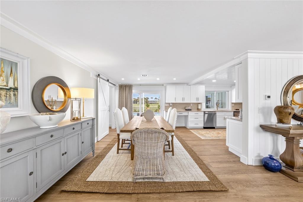 Open-concept dining area featuring wood-finish flooring, a long dining table, and a sliding barn door