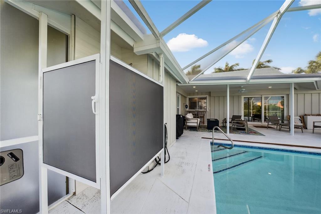 Screened lanai featuring a swimming pool with integrated steps, a covered patio area, and sliding glass doors leading into the residence