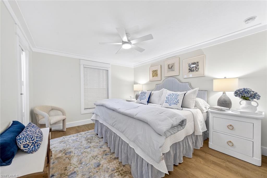 Spacious room featuring wood-finish flooring, a ceiling fan, crown molding, a window with blinds, and painted walls