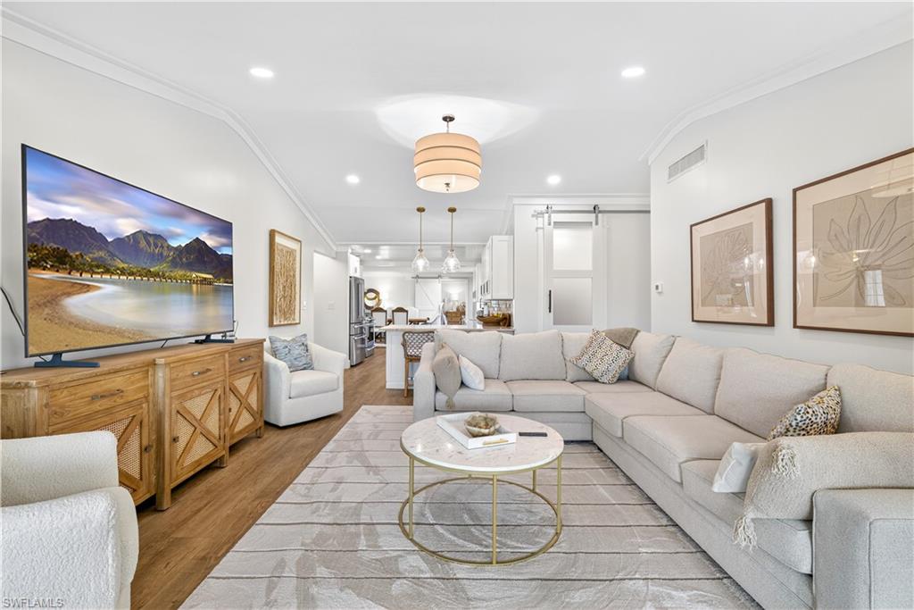 Open-concept living area featuring wood-finish flooring, recessed lighting, and crown molding